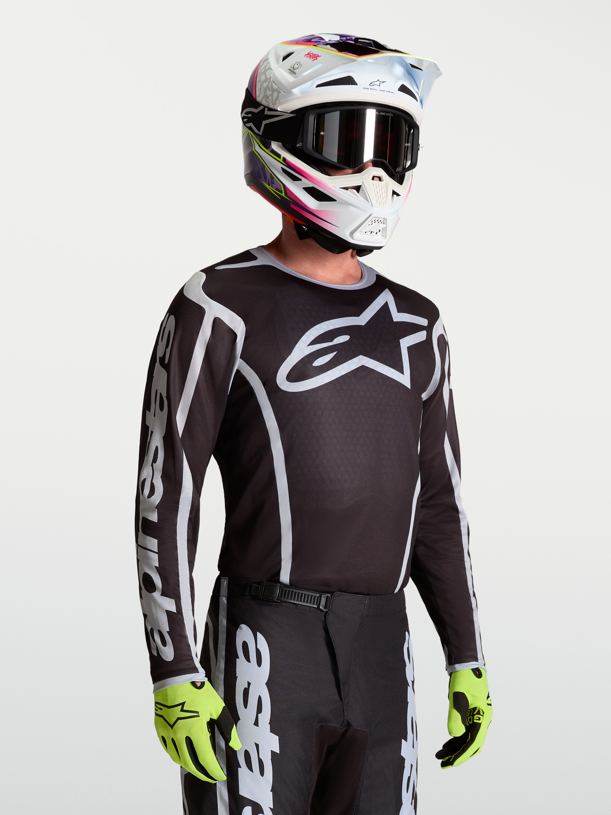 Koszulka Fluid Apex V2 Alpinestars, męska koszulka motocrossowa, czarna i srebrna, oddychający poliester odprowadzający wilgoć, na modelu w kasku.