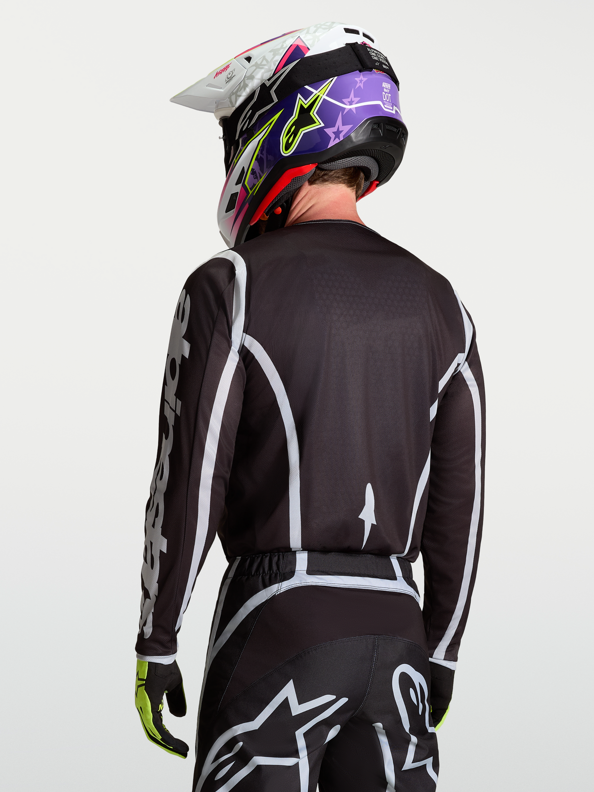 Alpinestars Koszulka Fluid Apex V2, czarna i srebrna, męska koszulka motocrossowa na modelu, widok z tyłu, sportowy krój, lekki i oddychający materiał poliestrowy do jazdy off-road.