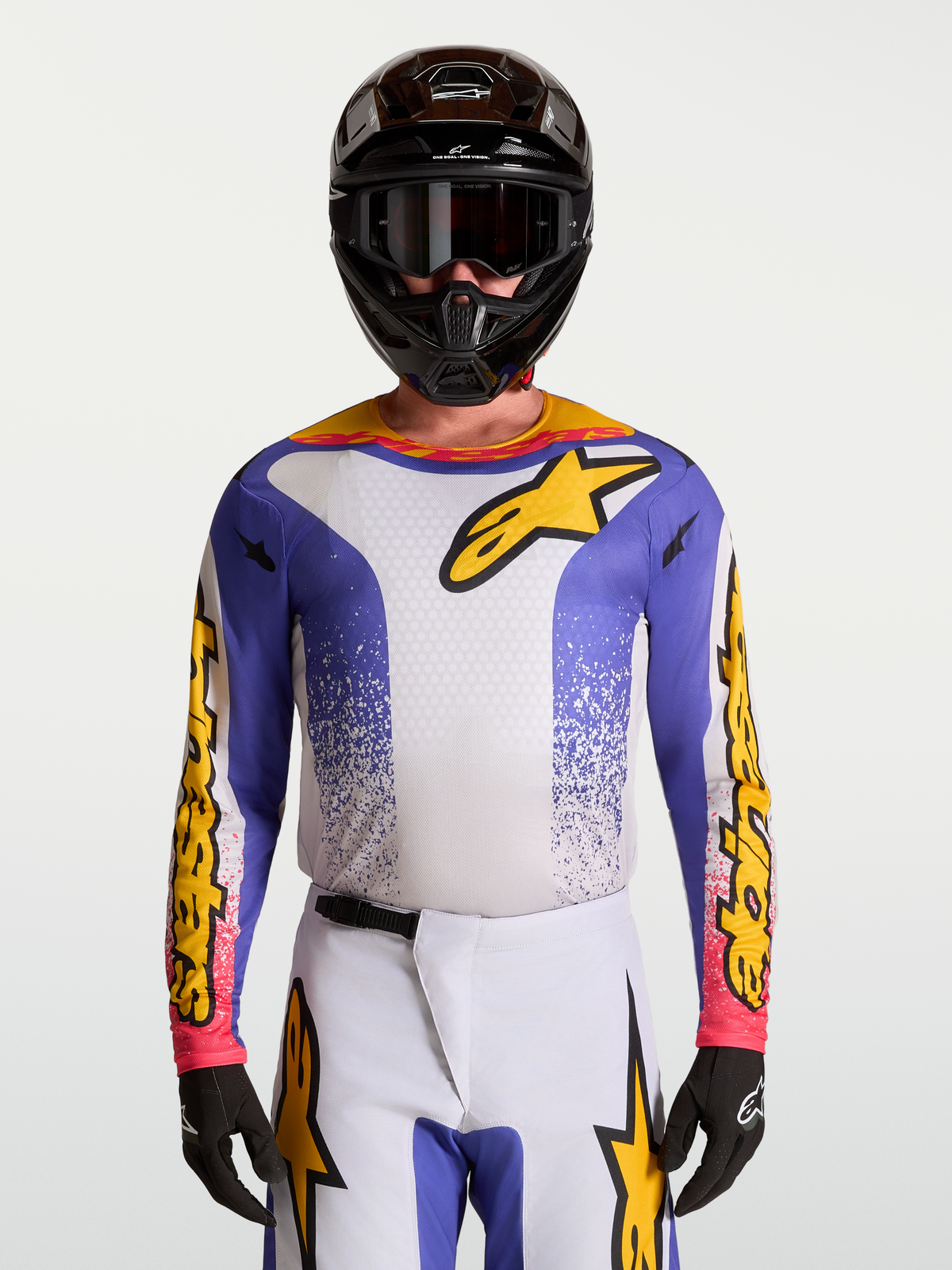 Koszulka Alpinestars Fluid Drag, męska koszulka motocrossowa, niebieska, biała i złota, lekki materiał odprowadzający wilgoć, sportowy krój, model w pełnym zestawie z kaskiem i rękawicami.