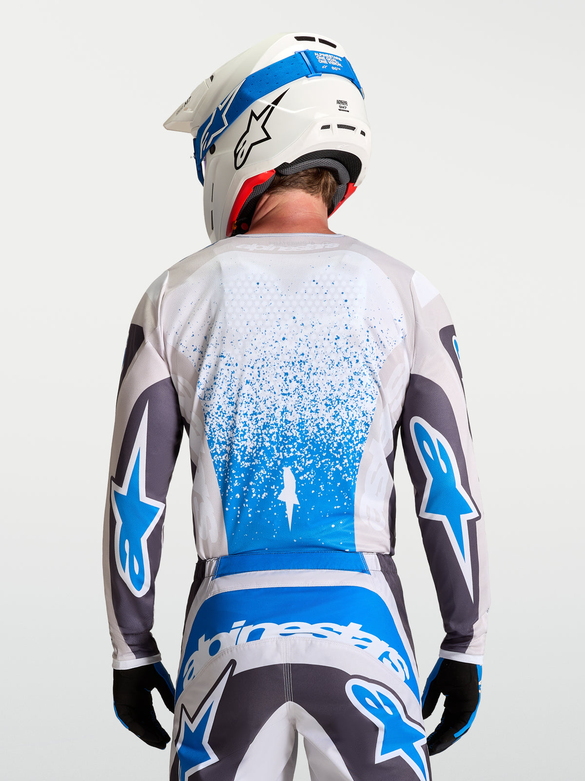 Alpinestars Koszulka Fluid Drag, męska koszulka motocrossowa w kolorze szarym i niebieskim, widok z tyłu na oddychający materiał i wydłużony krój do jazdy off-road.