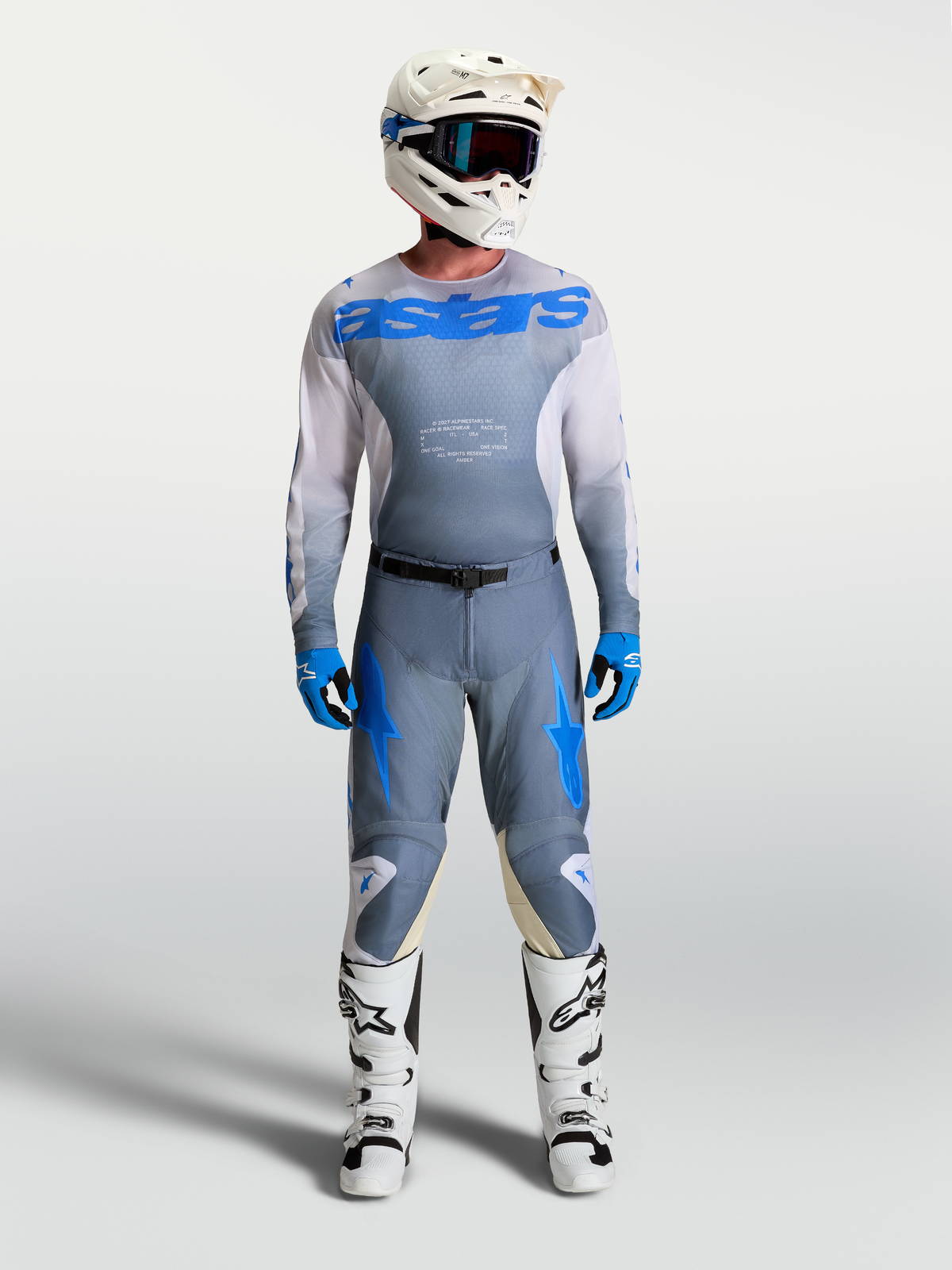 Alpinestars Racer Amber, męska koszulka i wyścigowy zestaw motocrossowy, szary i niebieski, biały kask oraz buty.