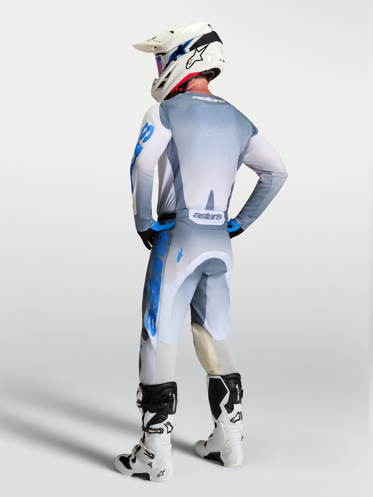 Alpinestars Spodnie Racer Amber i zestaw Gear Set, szare i niebieskie spodnie motocrossowe, widok z tyłu na zawodniku.
