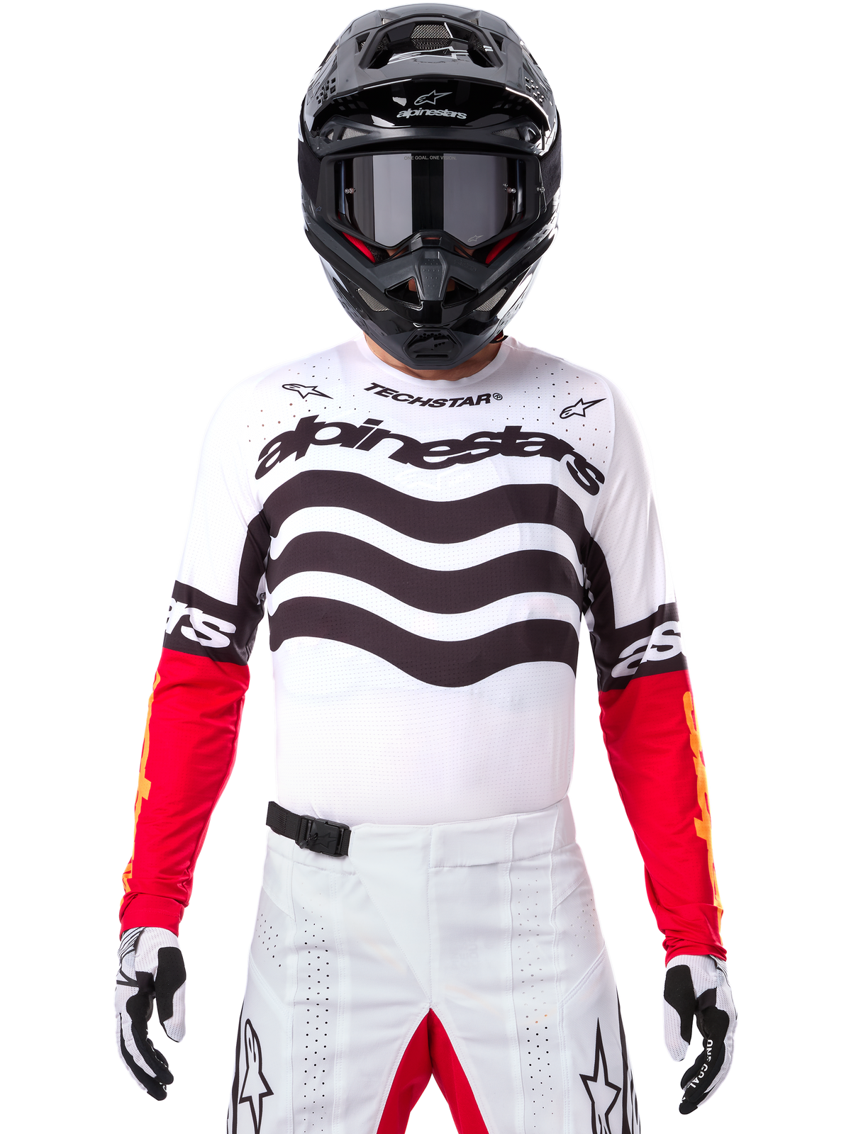 Motocross rider wearing complete racing gear, Limited Edition Techstar Deep Jersey in white and black with red sleeves, featuring wavy graphics and bold Alpinestars branding, white motocross pants, black helmet and goggles, coordinated outfit for off-road racing