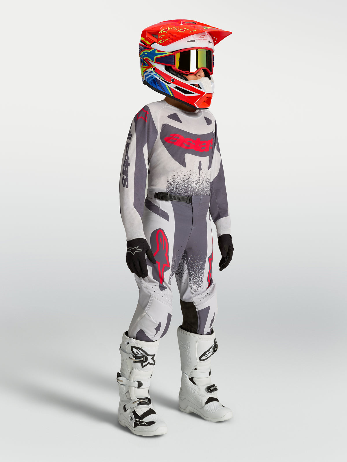 Młodzieżowy zestaw i koszulka Alpinestars Supertech Swan, szaro-czerwony fluo strój motocrossowy i białe buty wyścigowe.