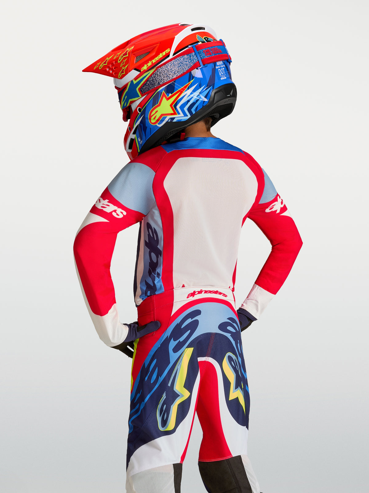 Alpinestars Koszulka Supertech Dyna Młodzieżowe 2027, koszulka motocrossowa, czerwona i granatowa, oddychająca siatka, widok z tyłu na zawodniku.