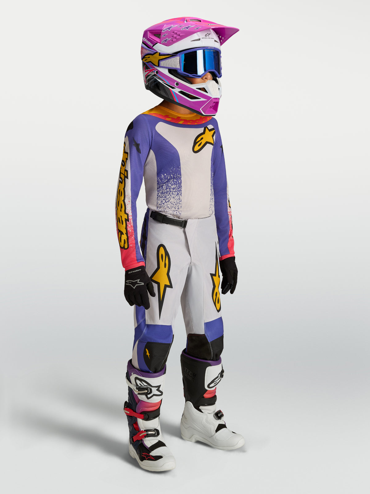 Alpinestars Youth Fluid Drag Gear Set, młodzieżowy strój motocrossowy, niebieski i biały z różowymi i złotymi akcentami.