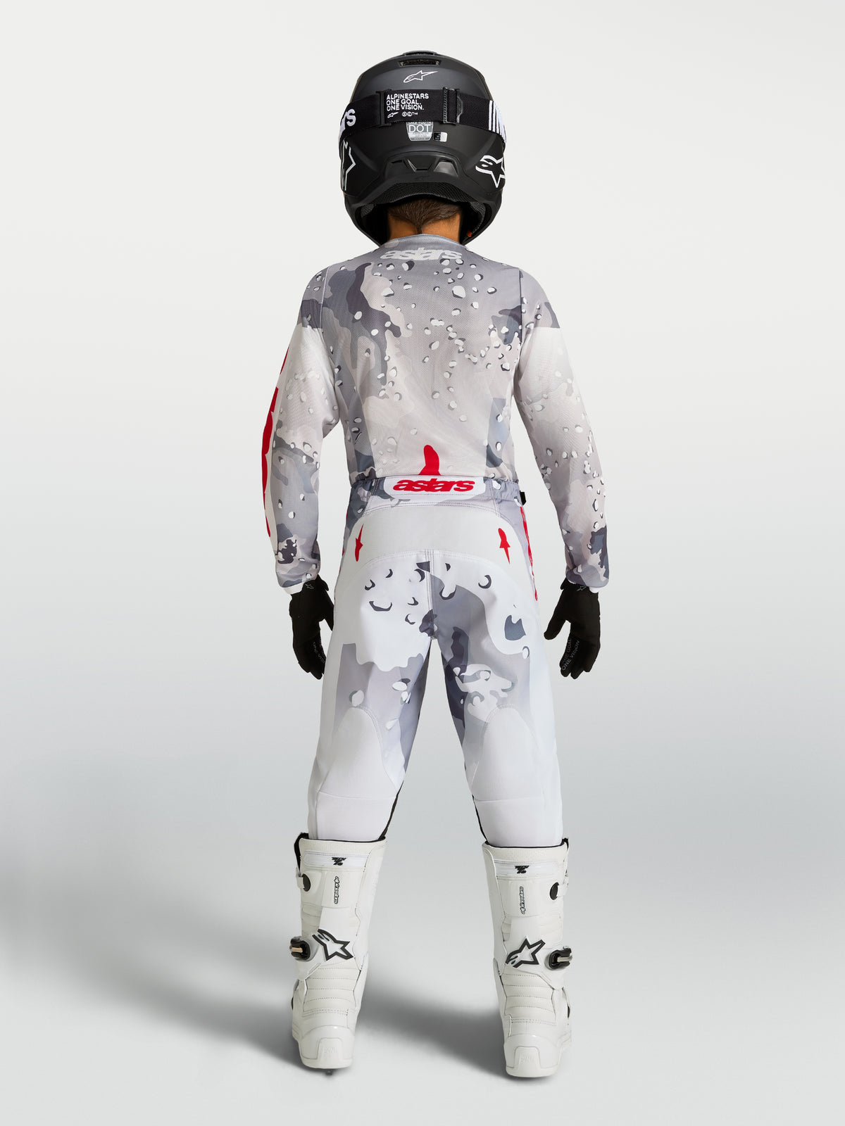 Alpinestars 2027 Youth Fluid Lone, zestaw motocrossowy, szary kamuflaż i biały z czerwonymi akcentami, widok od tyłu.