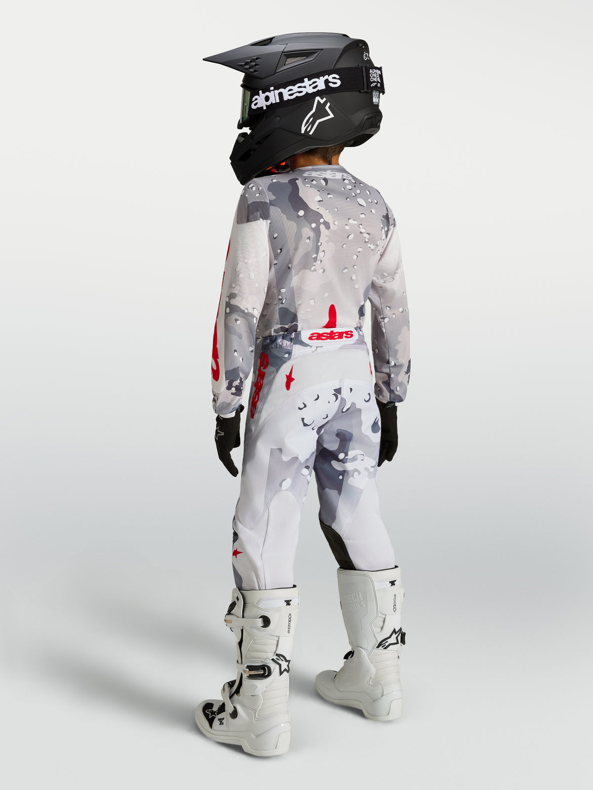Alpinestars 2027 Fluid Lone, młodzieżowy zestaw, szary kamuflaż i biały, czerwone akcenty, widok z tyłu na modelu.