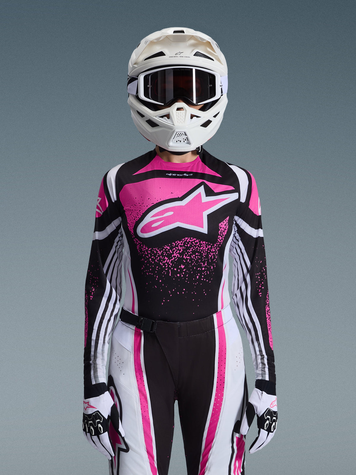 Alpinestars 2026 Stella Techstar Nomur Gear Set, damski strój motocrossowy, różowo-czarno-biały z dużym logo gwiazdy, dopasowana koszulka, spodnie i rękawice, biały kask, widok z przodu na szarym tle