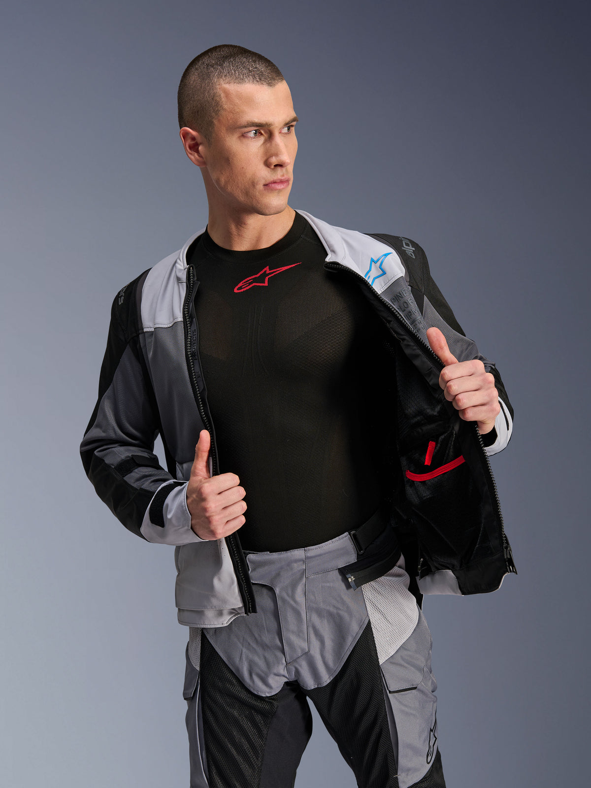 Kurtka Alpinestars ST-2 Air, Ice Gray Dark Gray Black, motocyklowa kurtka turystyczna, rozpięta, aby pokazać wewnętrzną podszewkę z siatki i kieszenie, w zestawieniu z pasującymi spodniami i czarną warstwą bazową