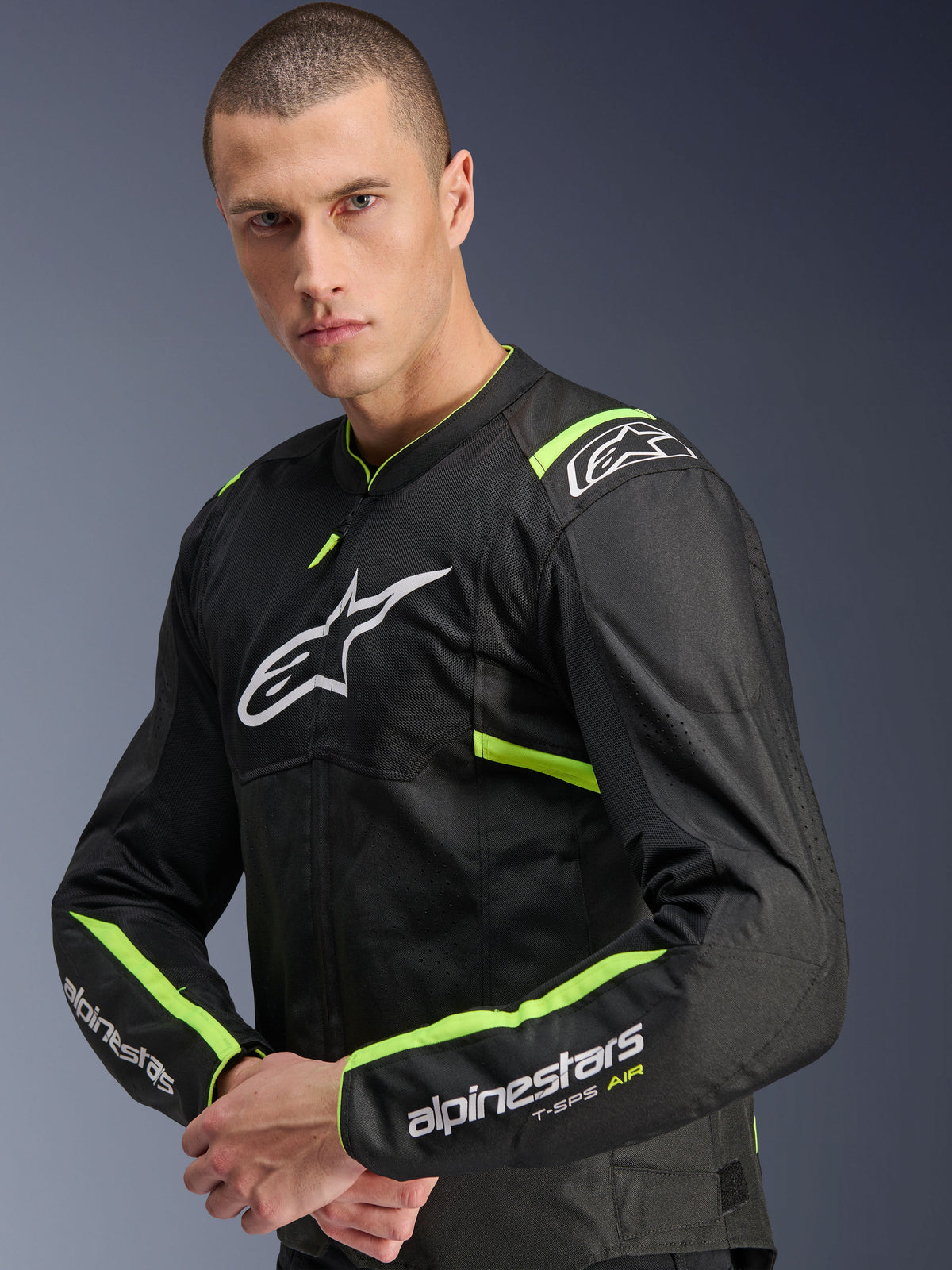 Alpinestars T-Sps Air V2 Jacket, kolor Black Yellow Fluo, tekstylna kurtka motocyklowa prezentowana na modelu, panele z siatki technicznej zapewniające przepływ powietrza, białe logo Alpinestars na klatce piersiowej oraz neonowe żółte akcenty na ramionach i rękawach.
