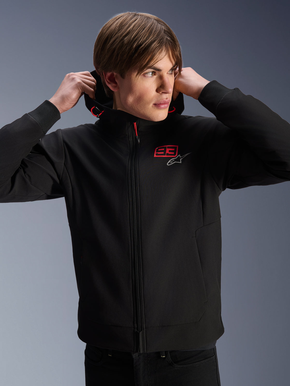 Alpinestars MM93 Radium Tech Hoodie, miejska kurtka motocyklowa, czarna z czerwonym i srebrnym logo, prezentowana na modelu, zamek na całej długości i prążkowane mankiety, casualowa odzież lifestyle motorsport