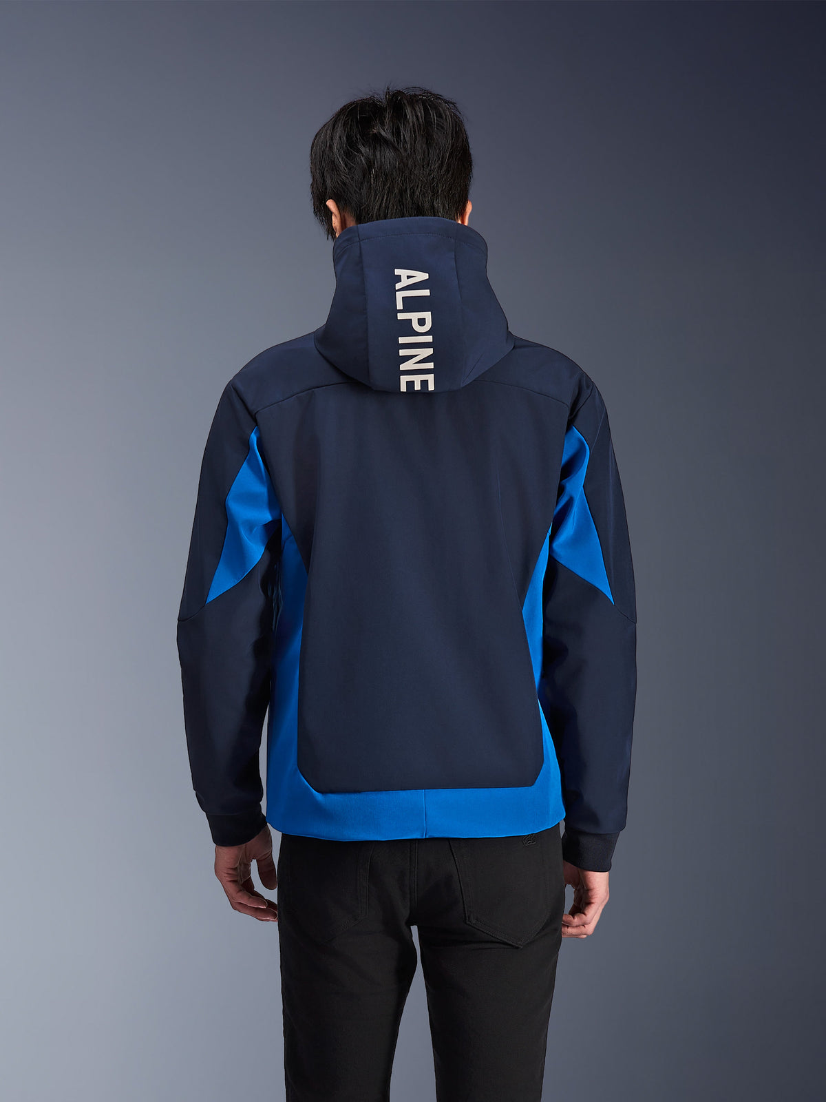 Alpinestars Radium Tech Hoodie, kurtka motocyklowa w kolorach Night Navy i Royal Blue, widok z tyłu prezentujący biały napis „ALPINE” na kapturze, miejska odzież techniczna o sportowym kroju z kontrastującymi panelami kolorystycznymi