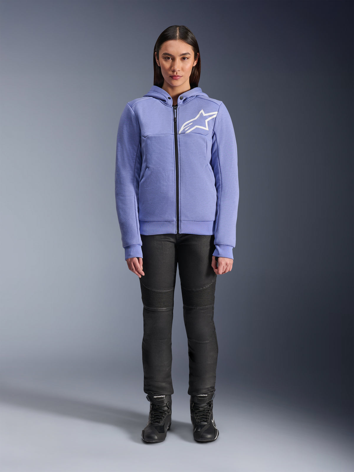 Alpinestars Woman Stella Chrome V2 Sport Hoodie, Blue Violet with white Astars logo on the chest, full-zip technical fleece with hood, worn with black motorcycle pants and riding boots, casual urban riding gear for women