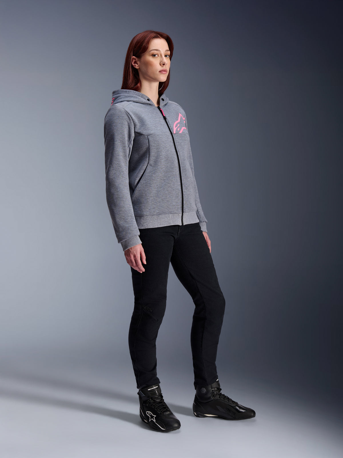 Alpinestars Stella Chrome V2 Sport Hoodie, damska bluza motocyklowa, szary melanż i różowy fluo, zestawiona z czarnymi spodniami do jazdy i czarnymi butami, miejska odzież motocyklowa w swobodnym stylu