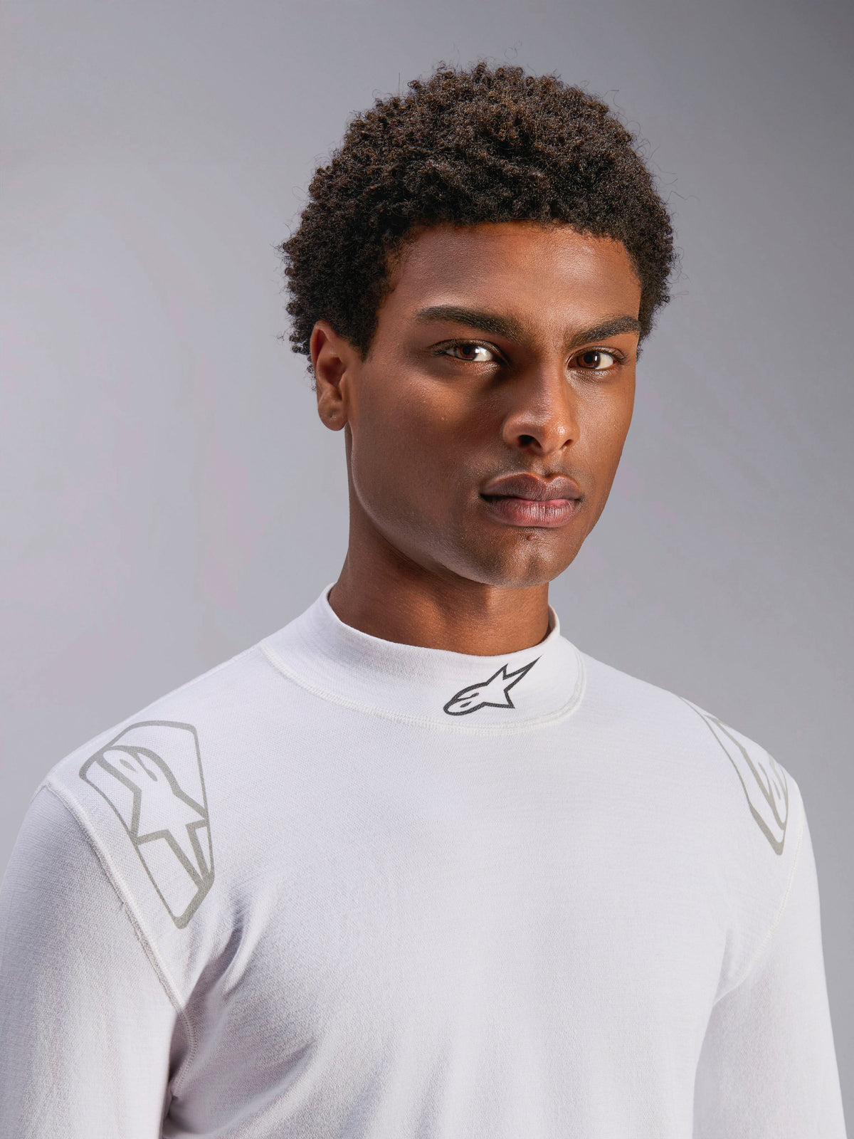 Alpinestars ZX Evo V3 Top - z długim rękawem, biała samochodowa bielizna rajdowa, prezentowana na modelu, stójka z czarnym logo Alpinestars, srebrne nadruki graficzne na ramionach, lekka i ognioodporna