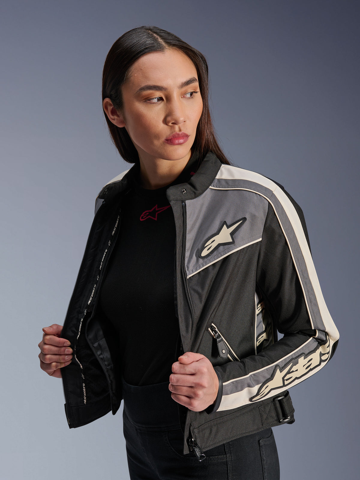 Damska kurtka Alpinestars Stella T-Dyno WR, tekstylna kurtka motocyklowa, czarna, ciemnoszara i ecru, design inspirowany stylem vintage ze sportowymi pasami i logo na piersi i rękawach, prezentowana przez modelkę, miejska odzież motocyklowa