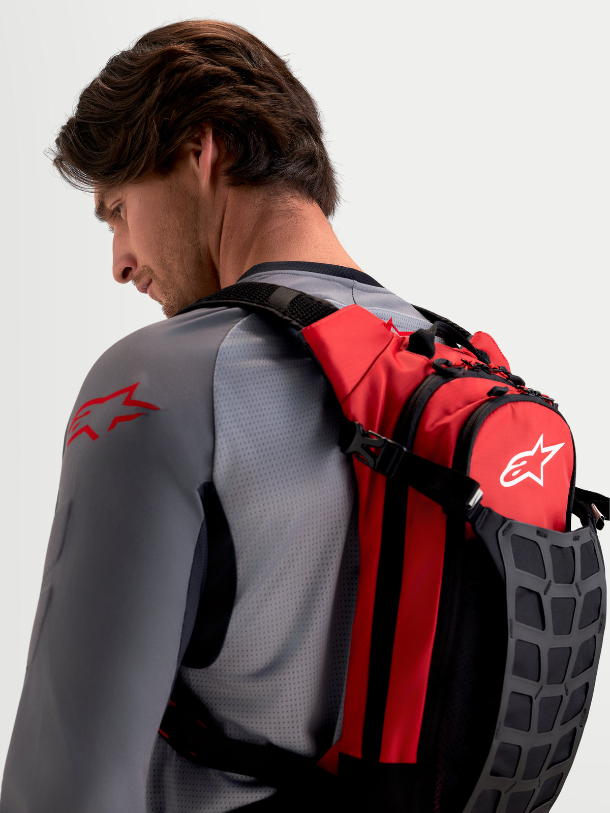 Alpinestars Plecak AT-9, plecak motocyklowy motocross, czerwony i czarny, na męskim modelu z wyściełanymi szelkami i uporządkowaną przestrzenią na niezbędne wyposażenie toru