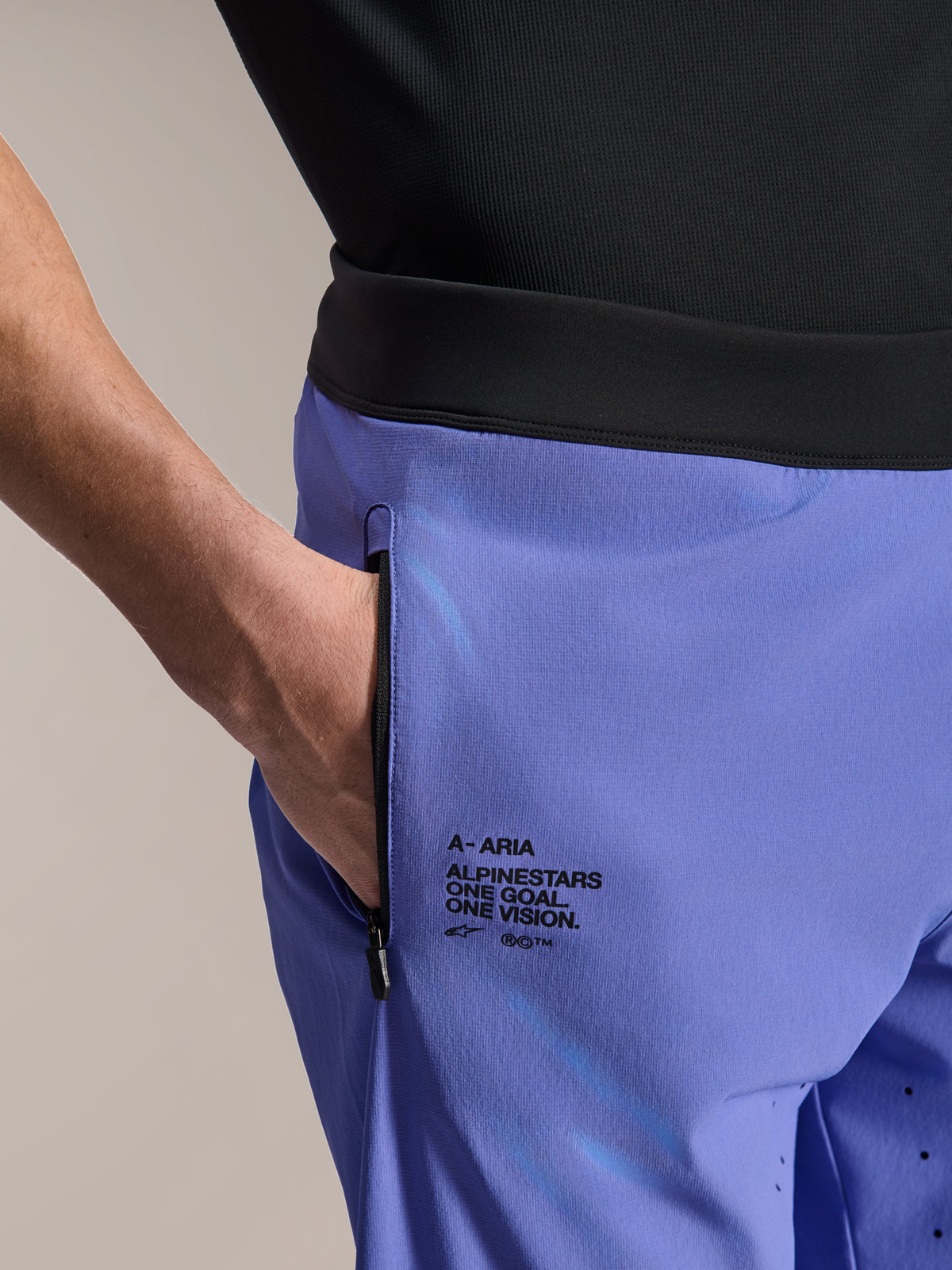 Alpinestars A-Aria Lite Short, szorty MTB, Baja Blue, zbliżenie na przednią kieszeń zapinaną na zamek i boczne logo z napisem „One Goal. One Vision.”, czarny pas i techniczny materiał do kolarstwa górskiego