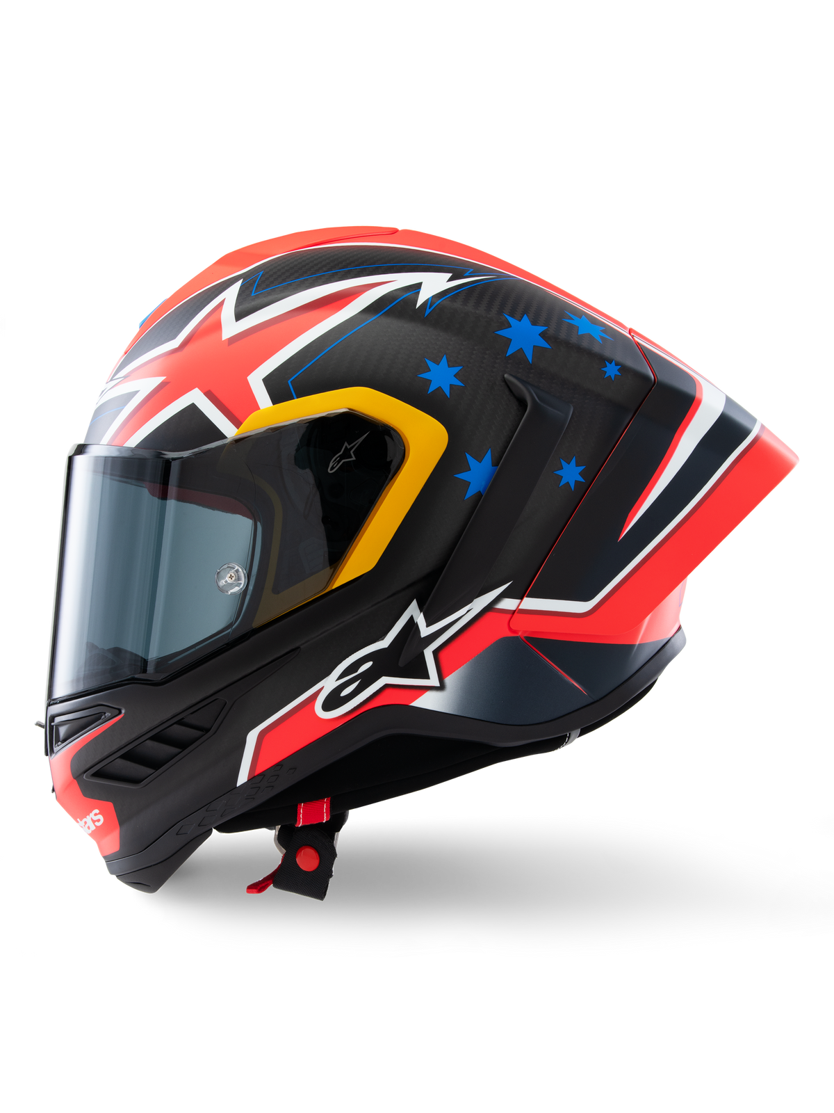 Kask Alpinestars Supertech R10 Miller Limited Edition, widok z boku, matowe wykończenie Carbon Red z widocznym splotem włókna węglowego, czerwono-biała grafika błyskawic, niebieskie gwiazdy z tyłu, żółte akcenty wokół wizjera i białe logo Alpinestars, wyczynowy wyścigowy kask motocyklowy