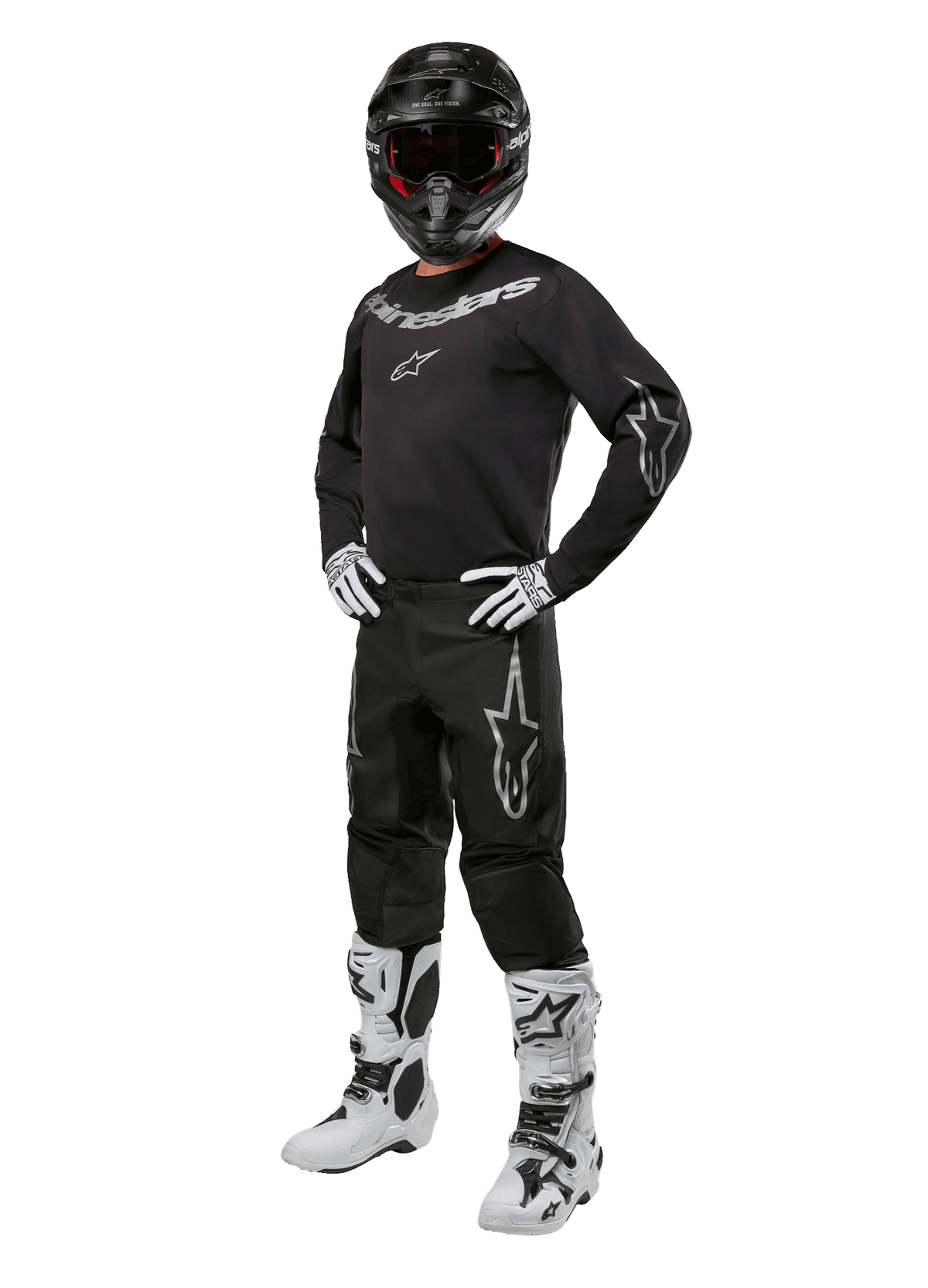 Alpinestars 2024 Fluid Graphite Gear Set, kompletny strój do wyścigów motocrossowych, czarny z szarymi i białymi logotypami, obejmujący koszulkę i spodnie noszone z dopasowanym czarnym kaskiem oraz biało-czarnymi rękawicami i butami, zaprojektowany z myślą o ochronie w terenie.