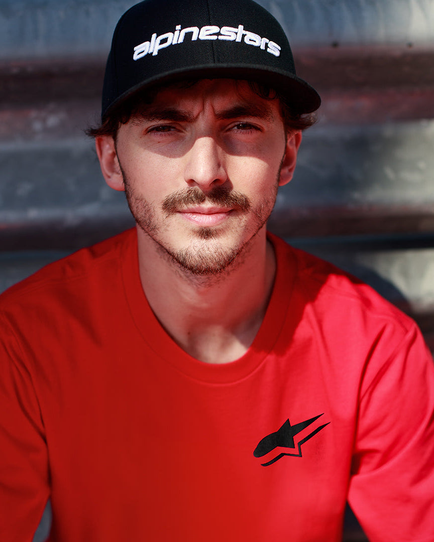 Alpinestars Formulate Csf Tee in Red, Francesco Bagnaia wearing short sleeve t-shirt with black Astars logo and black baseball cap, casual motorsport streetwear
