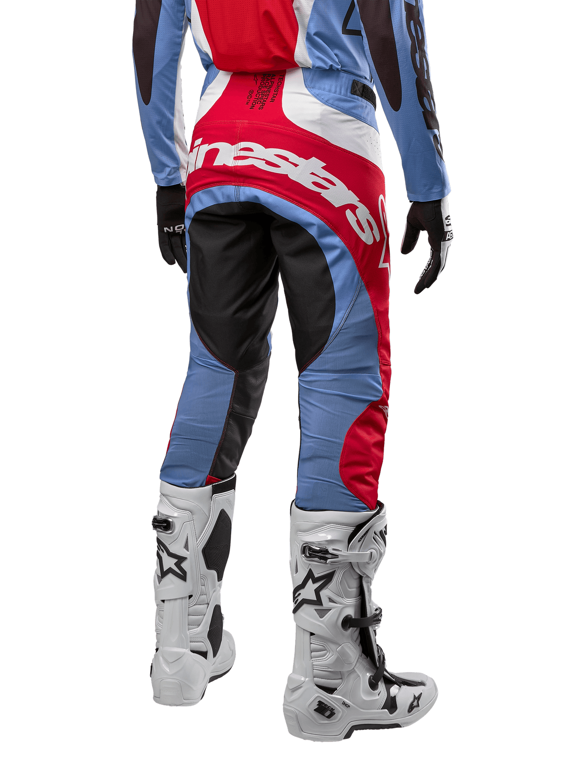 Spodnie Alpinestars Techstar Ocuri 2024, spodnie motocrossowe, jasnoniebieskie, czerwone i białe, widok z tyłu eksponujący duże czerwone logo Alpinestars na siedzeniu, zestawione z białymi butami wyścigowymi i dopasowaną bluzą.