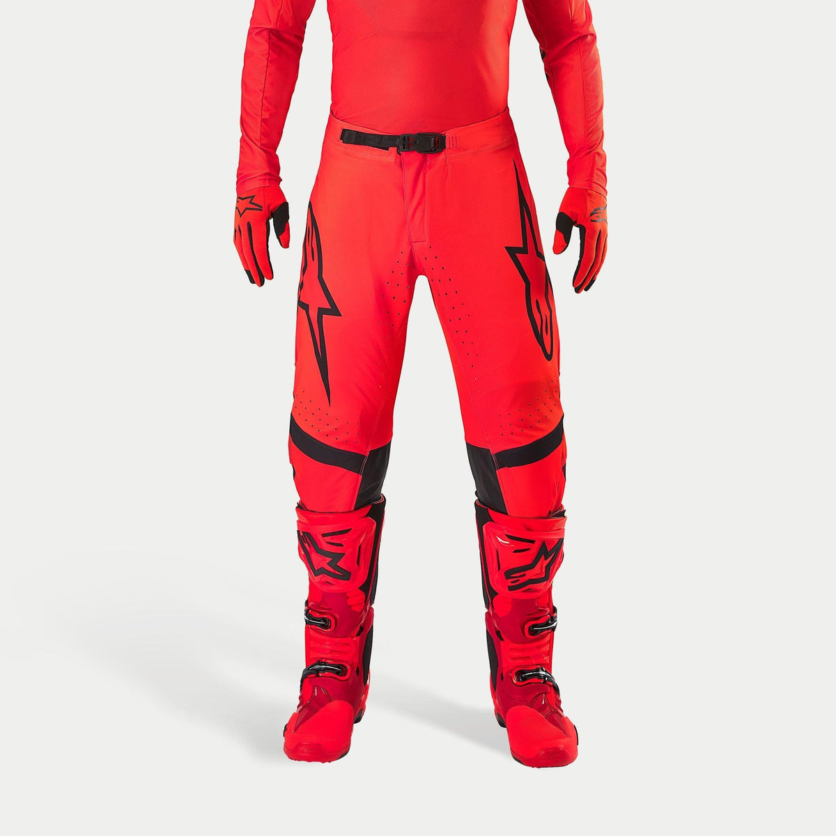 Alpinestars Supertech Ember LE Pants, Motocross Pants, Red Fluo and Bright Red with Black accents, featuring bold black star logos on the thighs, black waist buckle and knee panels, worn with matching red boots and gloves for a coordinated racing outfit.