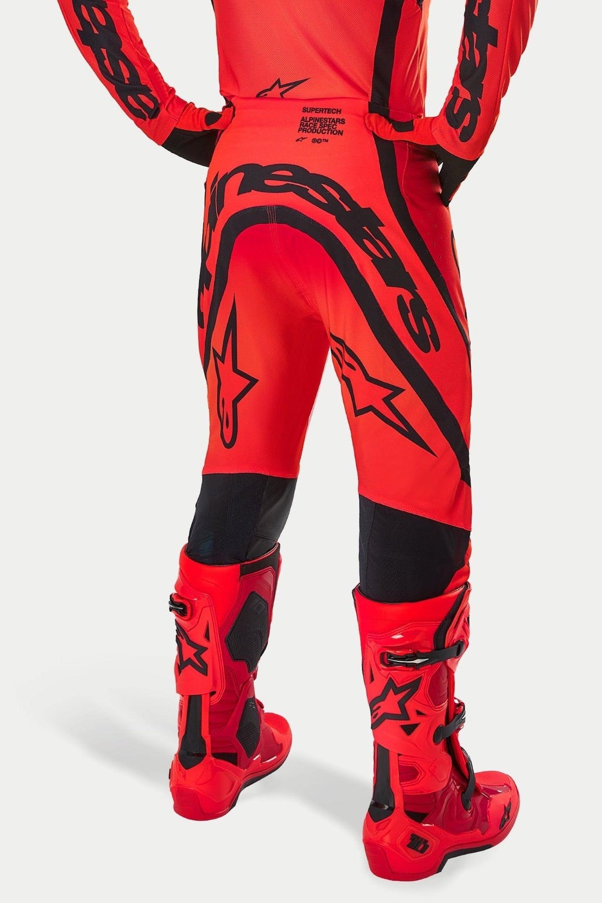 Alpinestars Supertech Ember LE Pants, Motocross Pants, Red Fluo Bright Red and Black, rear view featuring large black branding on the seat and star logos, worn with matching red motocross boots, professional racing gear for off-road performance