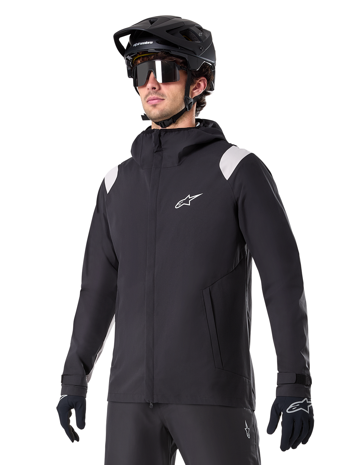 Alpinestars A-Dura Rain Jacket, Mountain Bike Rain Jacket, Black with light gray shoulder accents, worn by a rider with a black MTB helmet and sunglasses, white chest logo, waterproof construction, coordinated with black pants and gloves for off-road cycling