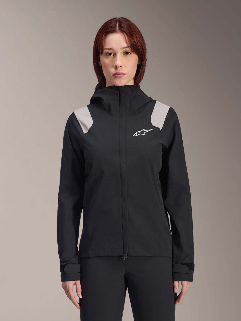 Alpinestars Stella A-Dura Rain Jacket, damska rowerowa kurtka przeciwdeszczowa, czarna z jasnoszarymi panelami na ramionach, techniczna kurtka z kapturem i białym logo na piersi, regulowane mankiety na rzepy, profesjonalna odzież do MTB i jazdy w deszczu