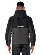 Kurtka Alpinestars Juncture Hybrid, widok z tyłu, czarny i gunmetal, casualowy anorak z mieszanych materiałów, góra z ripstopu i dół z polaru płóciennego, logo Alpinestars na plecach, noszona z ciemnymi spodniami