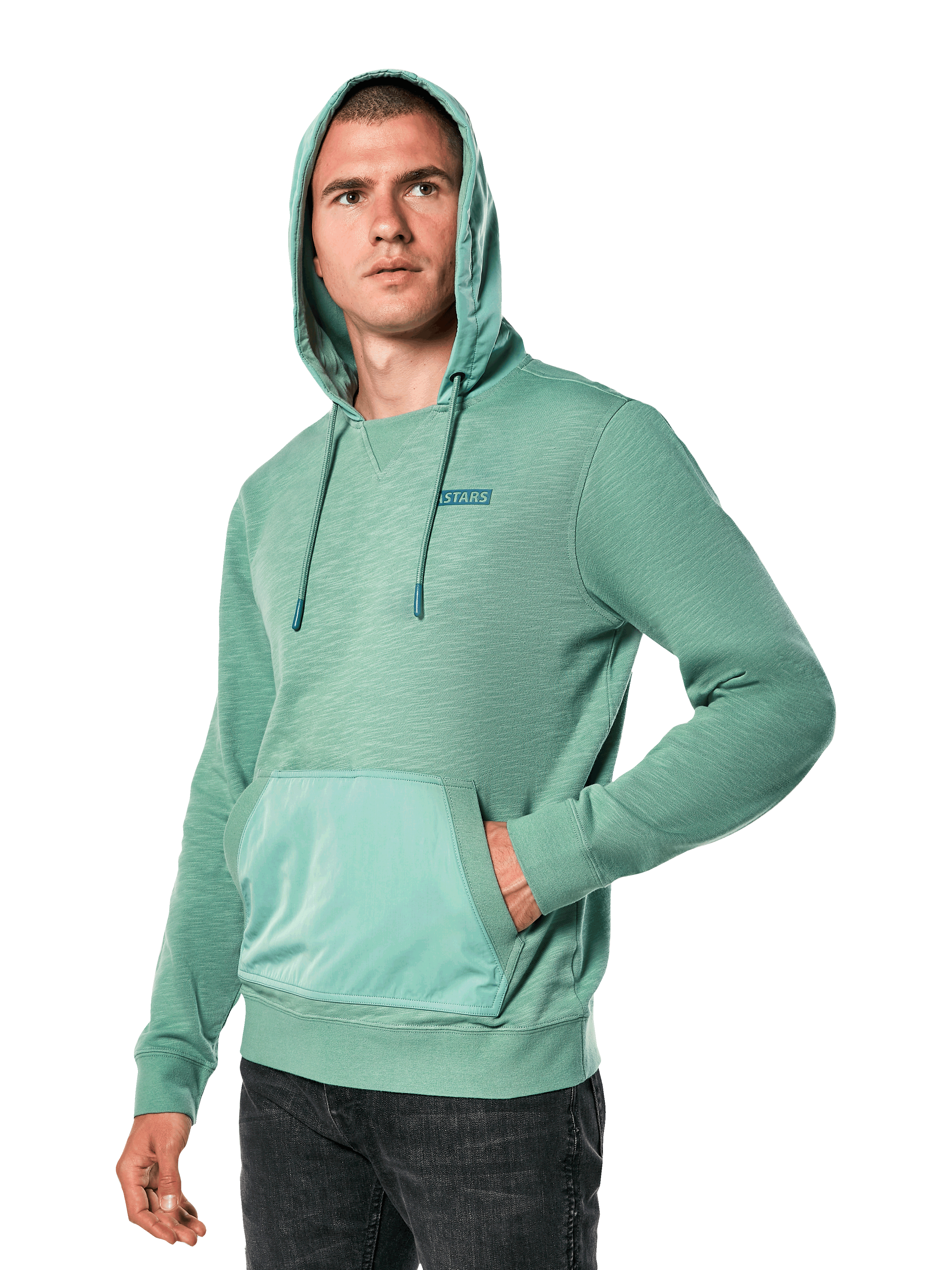 Alpinestars Rooted Hoodie, zielona bluza z kapturem z dzianiny French terry typu slub, kieszeń typu kangurka, małe logo STARS na piersi, model z założonym kapturem i ręką w kieszeni, streetwear inspirowany sportami motorowymi