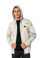 Alpinestars Plenitude Hoodie, casualowa odzież sportowa, polarowa bluza w kolorze złamanej bieli rozpinana na zamek, szare grafiki logo na całej powierzchni, noszona przez mężczyznę z założonym kapturem na czarną koszulkę, mała naszywka z logo na piersi i kieszeń typu kangurek