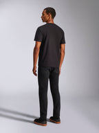 Alpinestars Ageless 2.0 CSF Tee, koszulka z krótkim rękawem, kolor czarny, widok z tyłu na modelu, noszona z czarnymi spodniami i butami na gumowej podeszwie, casualowa odzież uliczna inspirowana motorsportem