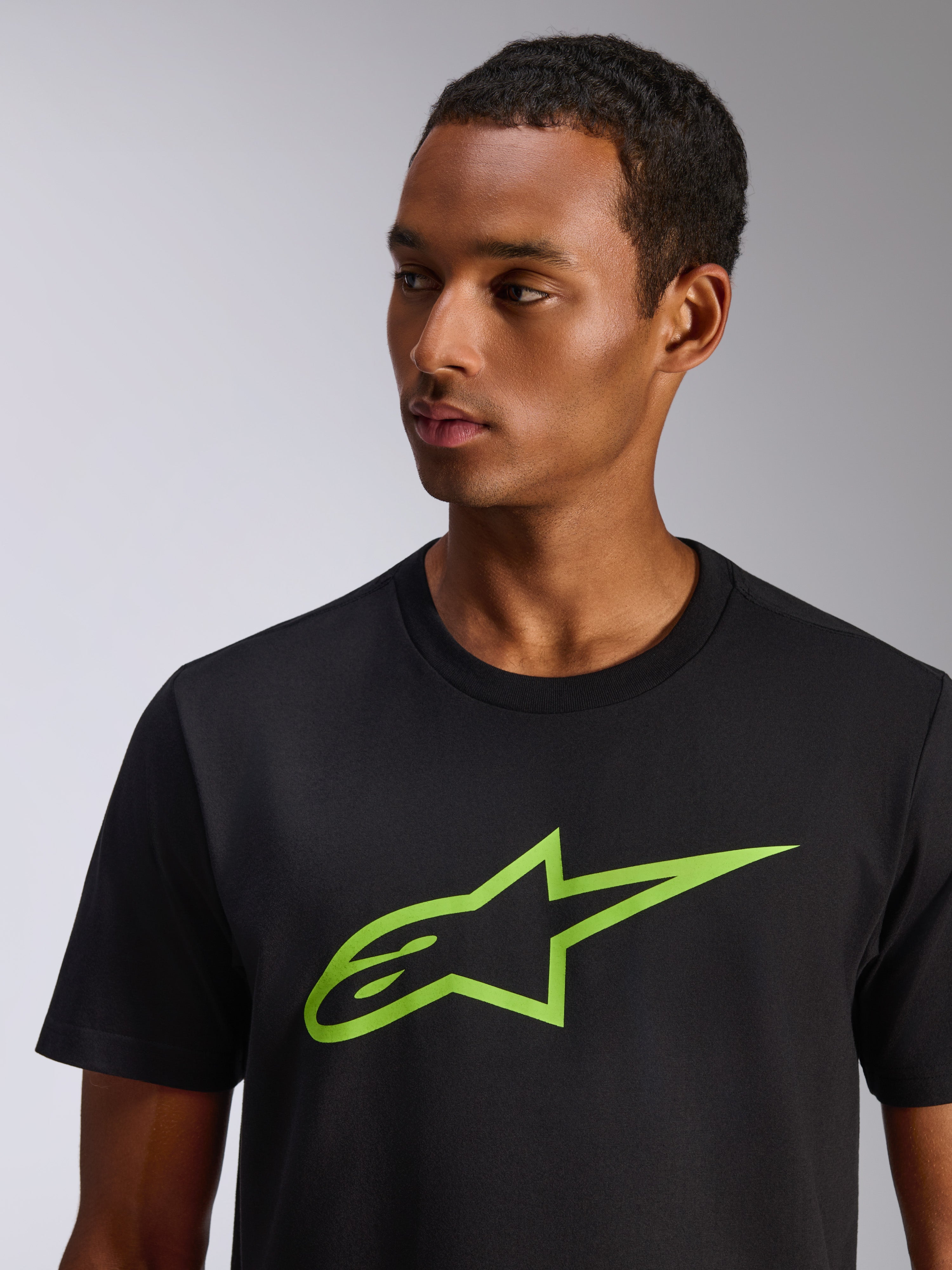 Alpinestars Ageless 2.0 CSF Tee, koszulka z krótkim rękawem, czarna z limonkowym logo Alpinestars w kształcie gwiazdy, prezentowana na modelu, codzienna odzież streetwear inspirowana sportami motorowymi