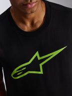 Alpinestars Ageless 2.0 CSF Tee, koszulka z krótkim rękawem, czarna z jaskrawozielonym logo gwiazdy, zbliżenie na grafikę na klatce piersiowej i dekolt, codzienna odzież motorsportowa typu streetwear