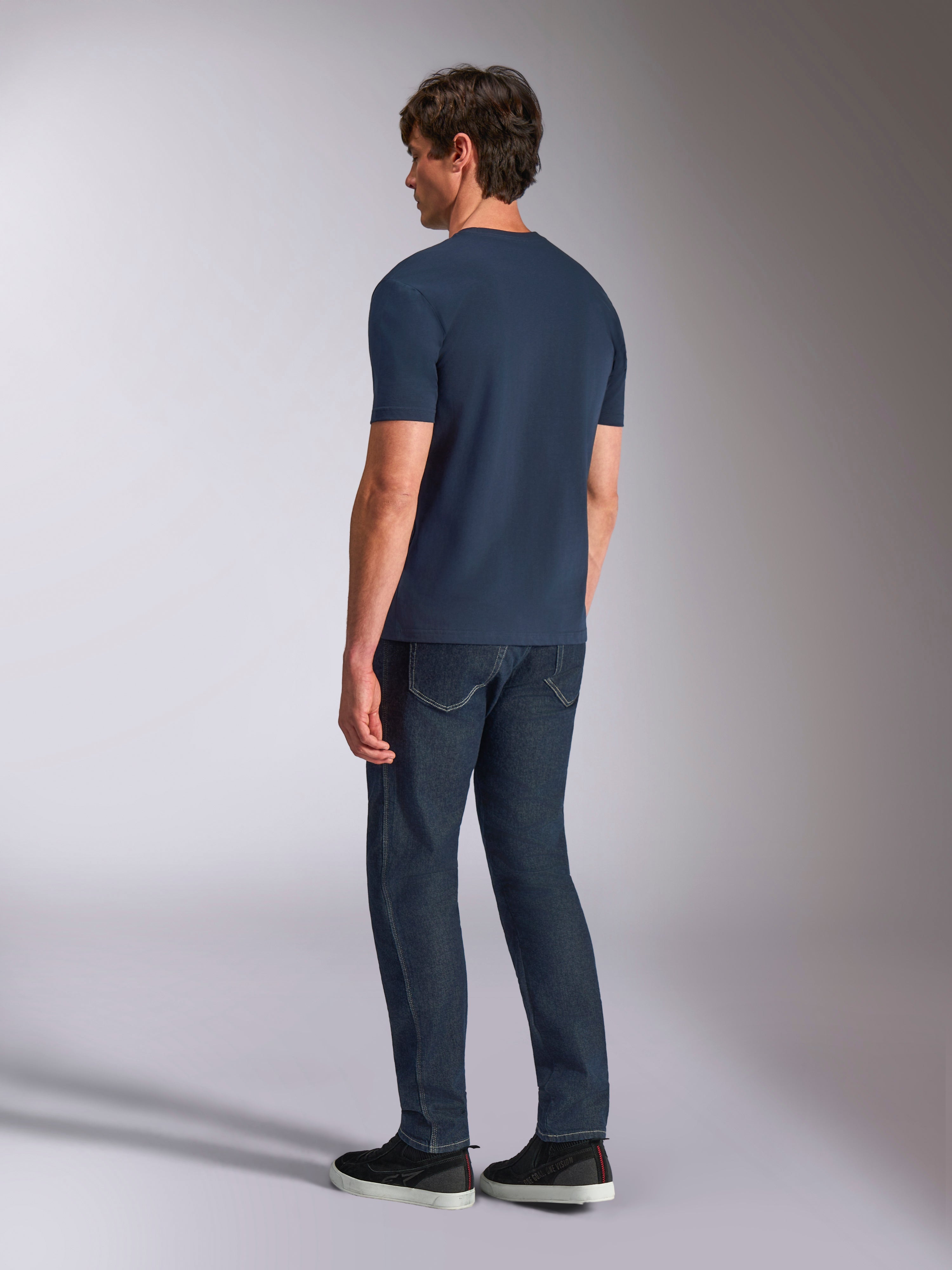 Alpinestars Ageless Shadow CSF Tee, koszulka z krótkim rękawem, granatowa, widok z tyłu na modelu, noszona z ciemnymi jeansami i czarnymi sneakersami, casualowy styl streetwear