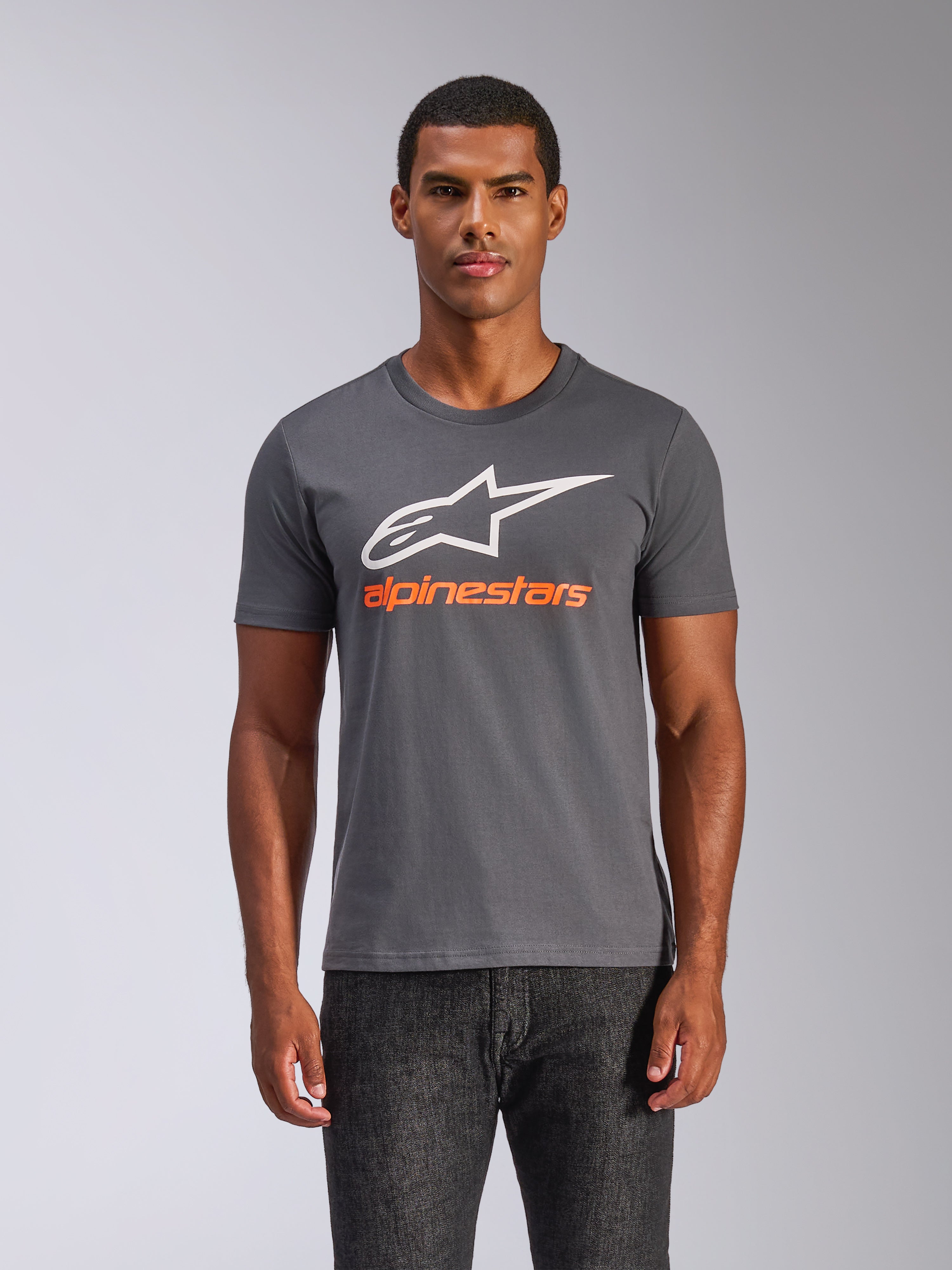 Alpinestars Always 2.0 CSF Tee, koszulka z krótkim rękawem, grafitowa, duże białe logo A-star i pomarańczowy napis Alpinestars, noszona przez mężczyznę, casualowa odzież streetwear w stylu motorsport