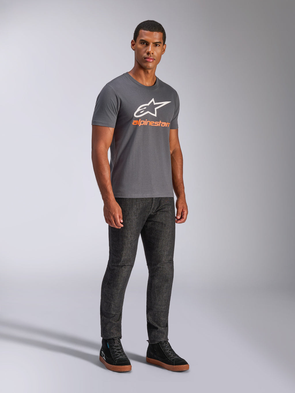 Alpinestars Always 2.0 CSF Tee, koszulka z krótkim rękawem, grafitowa, białe logo A-star z pomarańczowym brandingiem, casualowa odzież streetwearowa w stylu motorsport noszona z ciemnymi jeansami i czarnymi sneakersami