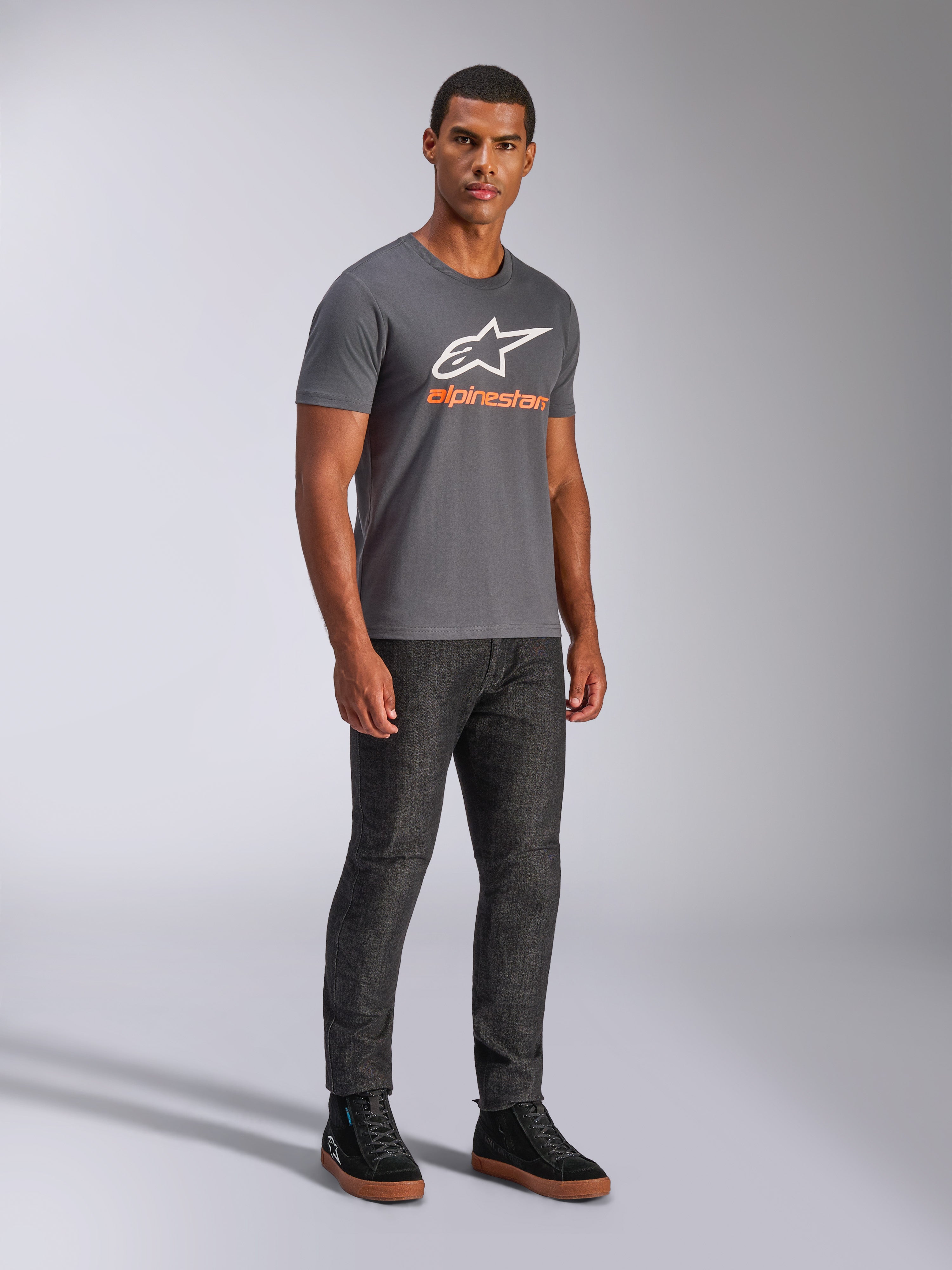Alpinestars Always 2.0 CSF Tee, koszulka z krótkim rękawem, grafitowa, białe logo A-star z pomarańczowym brandingiem, casualowa odzież streetwearowa w stylu motorsport noszona z ciemnymi jeansami i czarnymi sneakersami