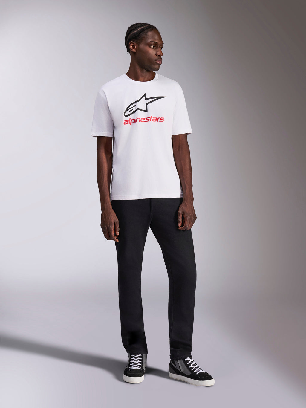 Alpinestars Always 2.0 CSF Tee, biała koszulka z krótkim rękawem, czarne logo Astar i czerwona grafika z napisem Alpinestars, model w czarnych spodniach i wysokich trampkach, codzienna odzież sportowa motorsport
