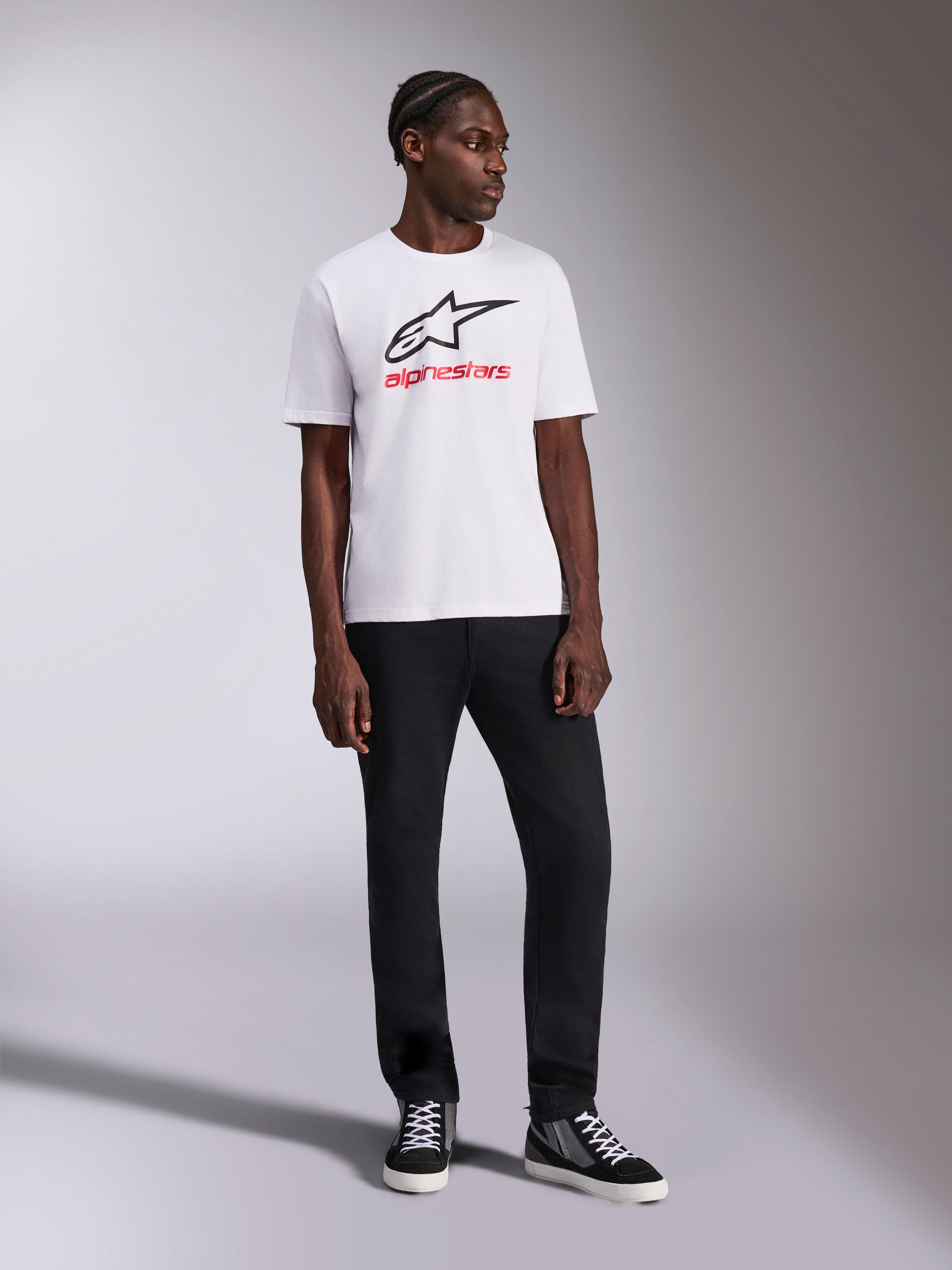 Alpinestars Always 2.0 CSF Tee, biała koszulka z krótkim rękawem, czarne logo Astar i czerwona grafika z napisem Alpinestars, model w czarnych spodniach i wysokich trampkach, codzienna odzież sportowa motorsport