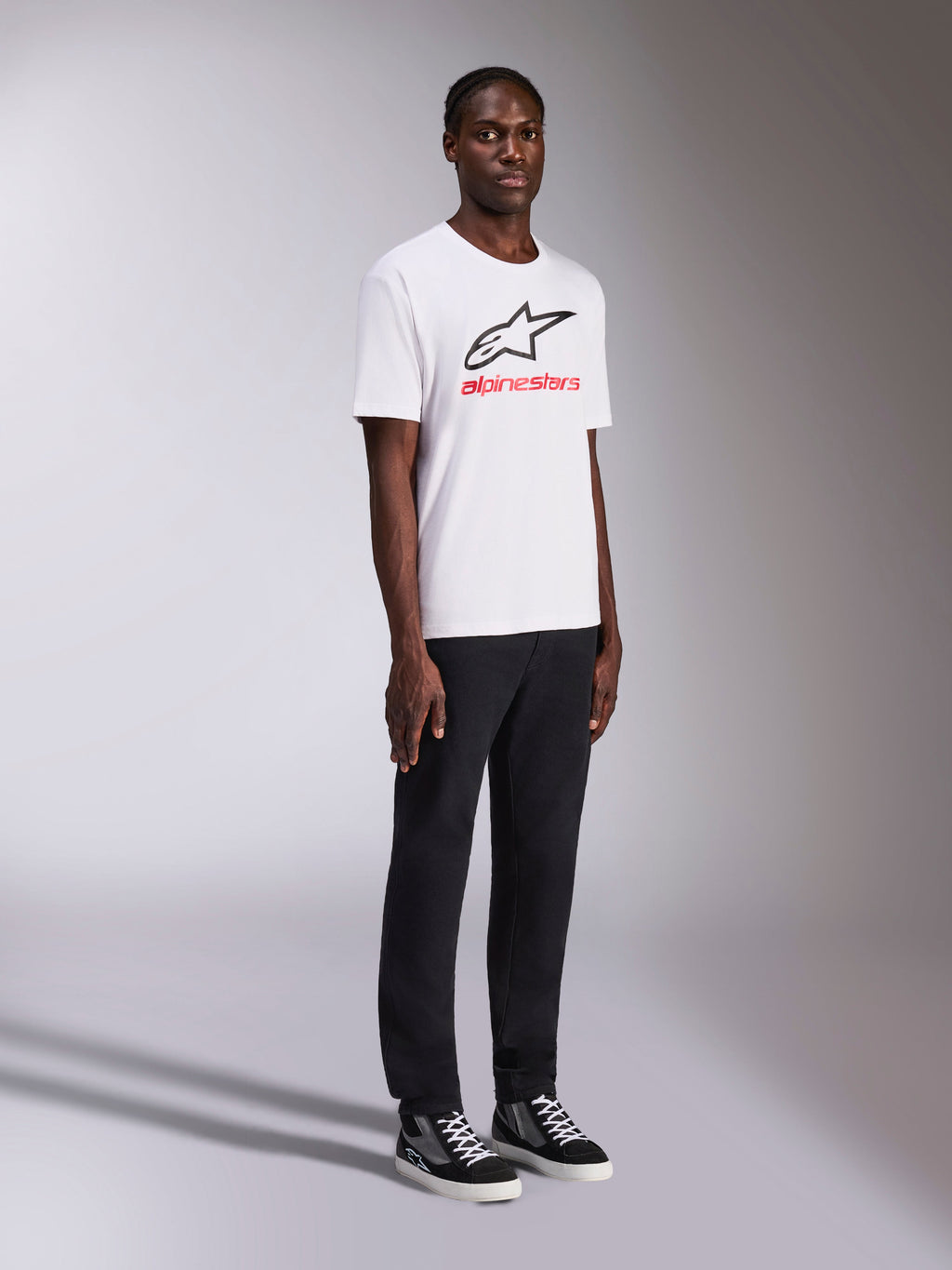 Alpinestars Always 2.0 CSF Tee, biała koszulka z krótkim rękawem, czarne logo Alpinestars i czerwony napis na piersi, model w czarnych spodniach i sneakersach, casualowa odzież streetwearowa