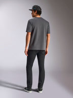 Alpinestars Blaze 2.0 CSF Tee, ciemnoszara koszulka z krótkim rękawem, widok z tyłu, noszona z czarnymi spodniami i czarną czapką z daszkiem typu mesh, codzienna odzież streetwearowa w stylu motorsport