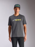Alpinestars Blaze 2.0 CSF Tee, t-shirt z krótkim rękawem, grafitowy, białe logo gwiazdy i żółta neonowa grafika stars, noszony z dopasowaną czapką typu trucker i czarnymi spodniami, casualowa odzież uliczna w stylu motorsport
