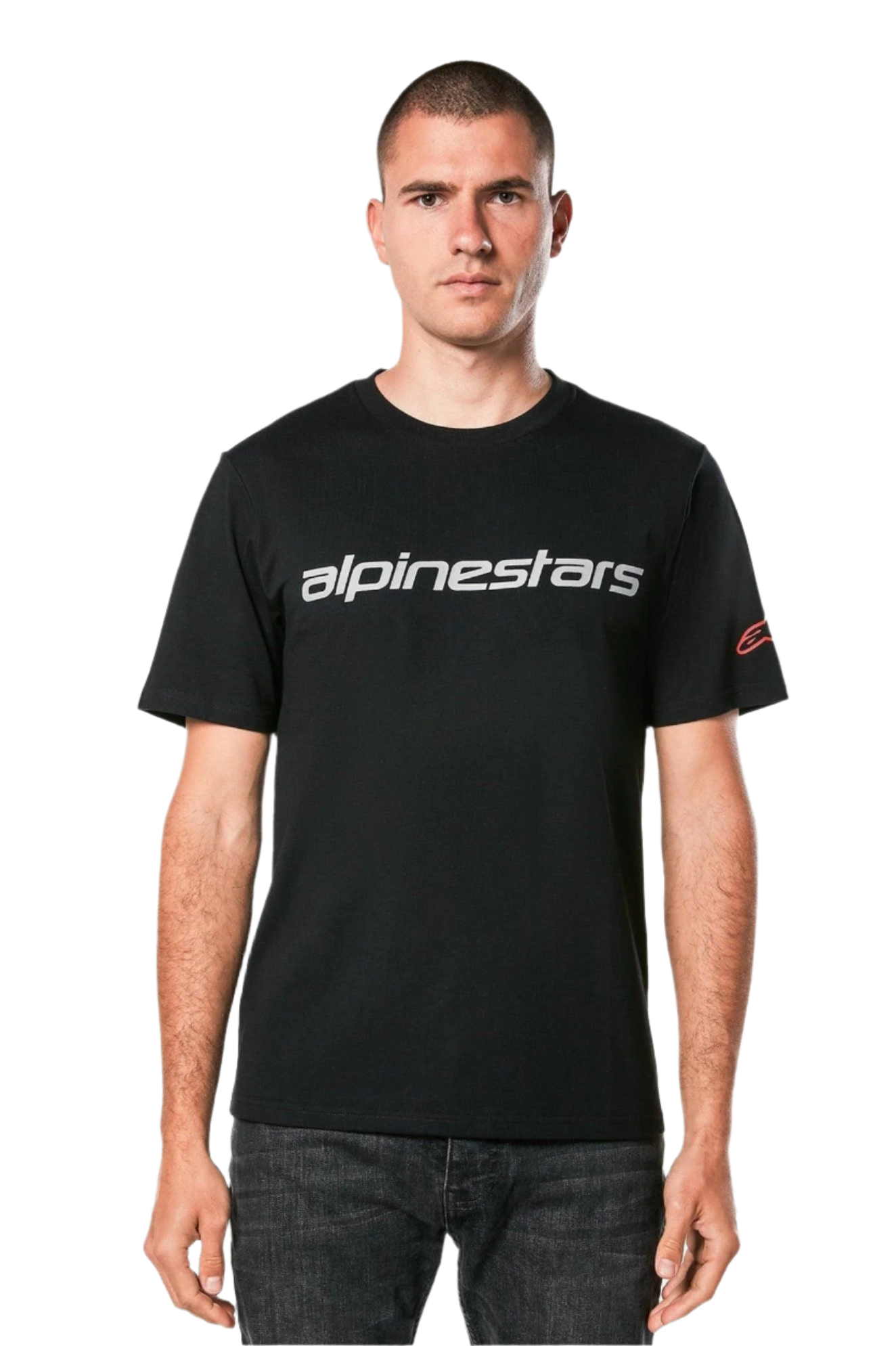 Koszulka Alpinestars Linear Wordmark 2.0 CSF, t-shirt z krótkim rękawem, czarny, szary linearny znak słowny na klatce piersiowej i czerwone logo Ageless na rękawie, noszona przez modela z ciemnymi jeansami, casualowy streetwear inspirowany sportami motorowymi