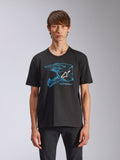 Alpinestars CSF Tee, czarna koszulka z krótkim rękawem, niebieska grafika przedstawiająca kask motocrossowy z białym logo Astars, codzienna odzież uliczna inspirowana sportami motorowymi, prezentowana przez modela