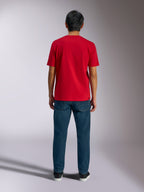 Alpinestars Ageless Shadow CSF Tee, widok z tyłu czerwonej koszulki z krótkim rękawem, zestawiona z ciemnoniebieskimi jeansami i czarnymi sneakersami, casualowy streetwear motorsportowy