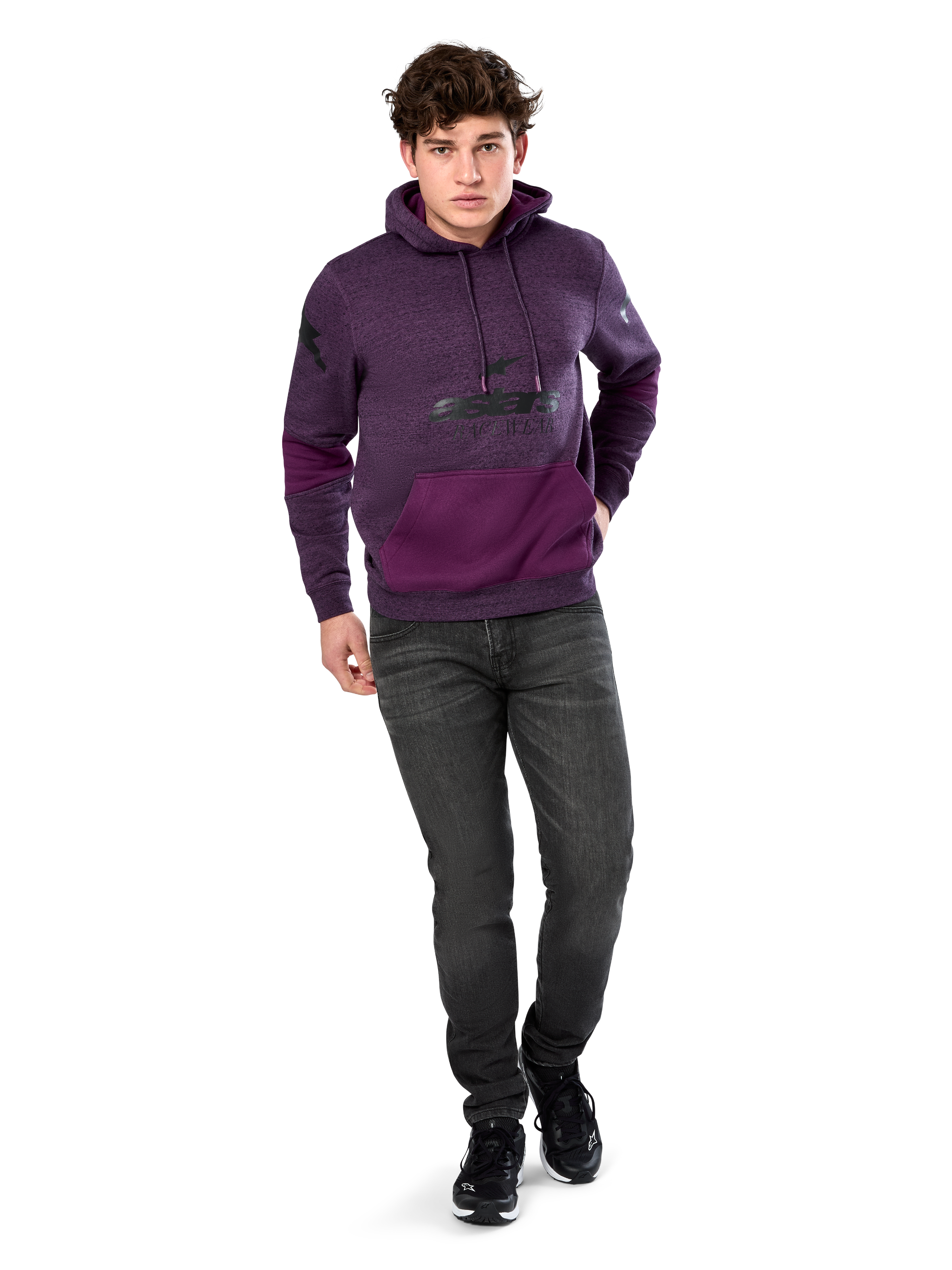 Alpinestars Perpetuate Hoodie, codzienna odzież streetwearowa, fioletowy polar melanżowy z ciemnofioletowymi wstawkami na kieszeni kangurce i rękawach, czarne logo na klatce piersiowej, kaptur ze sznurkiem, noszona przez modela z ciemnoszarymi dżinsami i czarnymi sneakersami